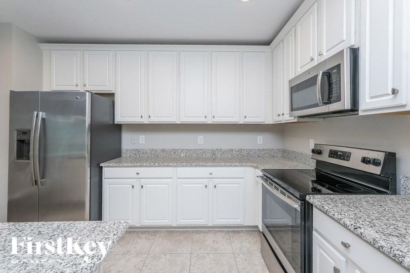 A kitchen with white cabinets and granite countertops.