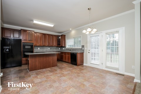 A kitchen with a black refrigerator and wooden cabinets.