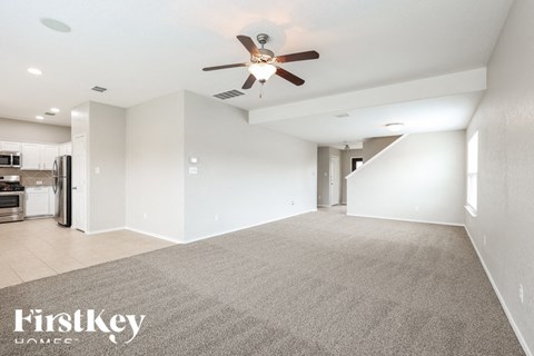 A spacious room with a carpeted floor and a ceiling fan.