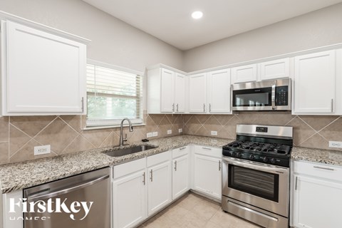 A kitchen with white cabinets and a granite countertop.