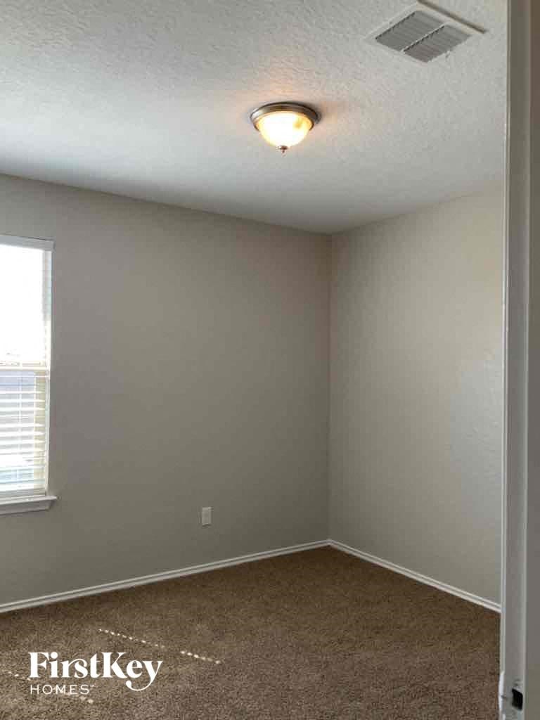 A room with a carpeted floor and a window with blinds.