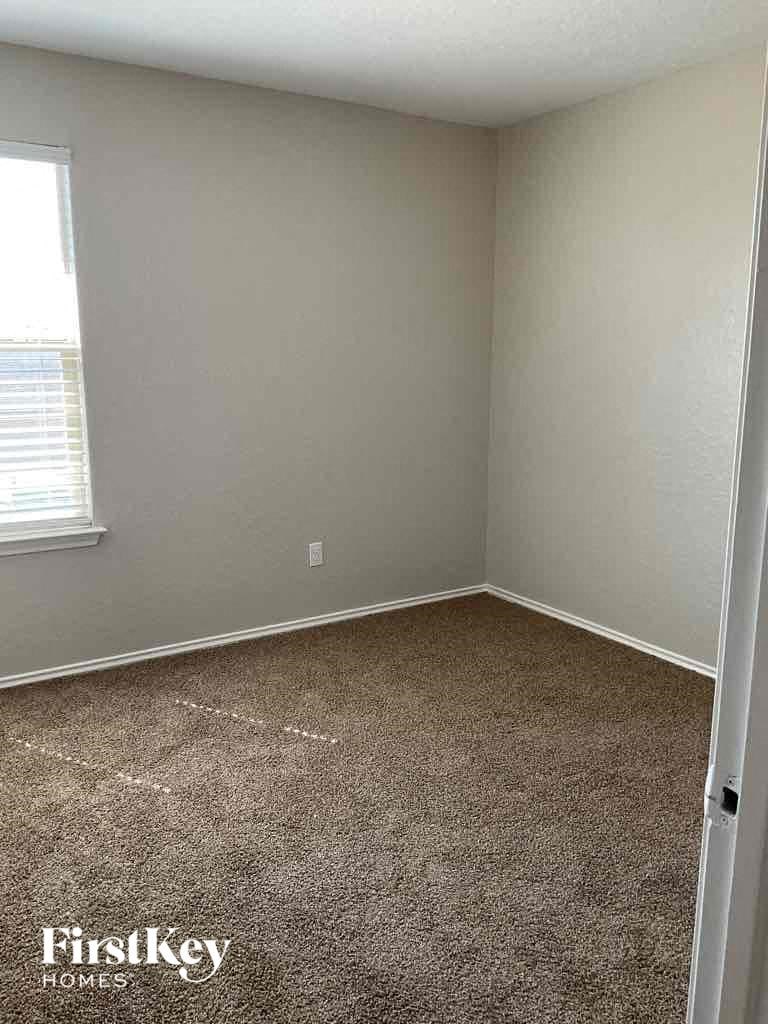 A room with a carpeted floor and a window with blinds.