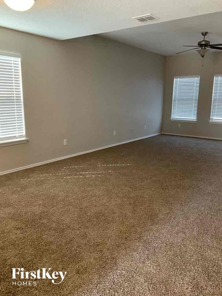 A room with a carpeted floor and a ceiling fan.
