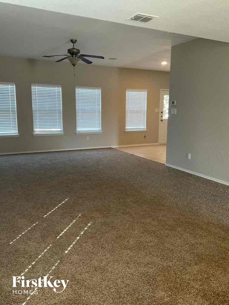 A room with a carpet floor and a ceiling fan.
