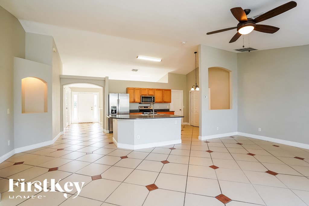an empty kitchen with a ceiling fan and tiled floor