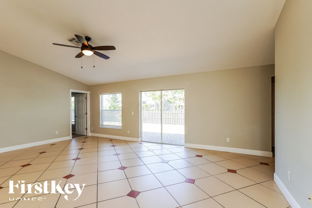 an empty living room with a ceiling fan and a door to a patio