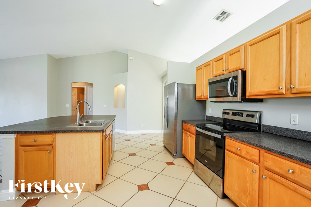 full view of the kitchen with wood cabinets and black counter tops