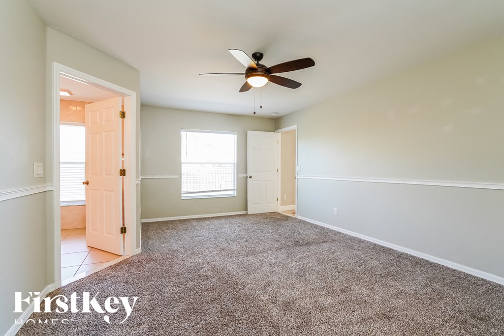 an empty living room with a ceiling fan and a carpet