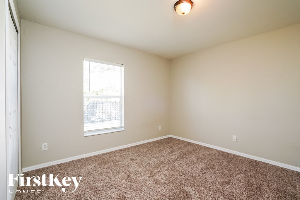 a bedroom with carpeted flooring and a window