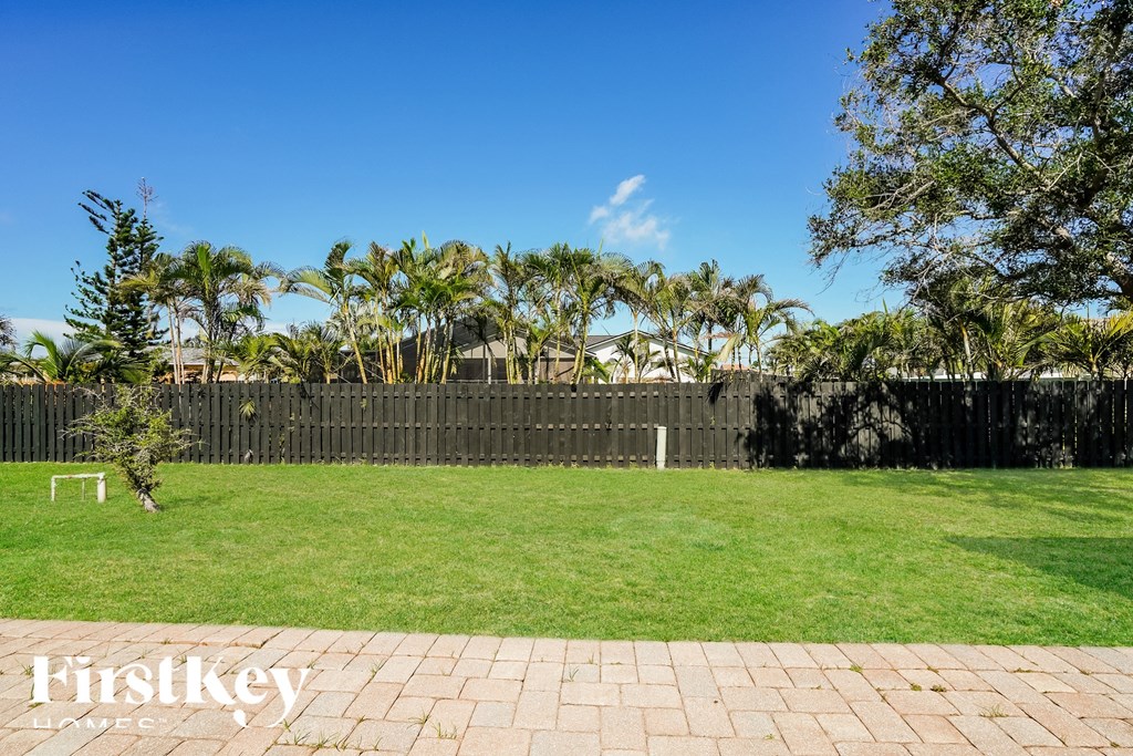 a backyard with a fence and palm trees