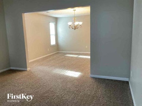 a empty living room with a chandelier and gray walls