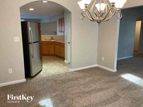 an empty kitchen with a refrigerator and a chandelier