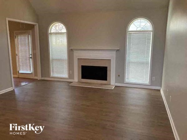 an empty living room with a fireplace and wood floors