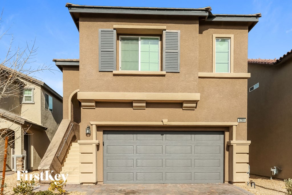 A two-story house with a garage door and a window.