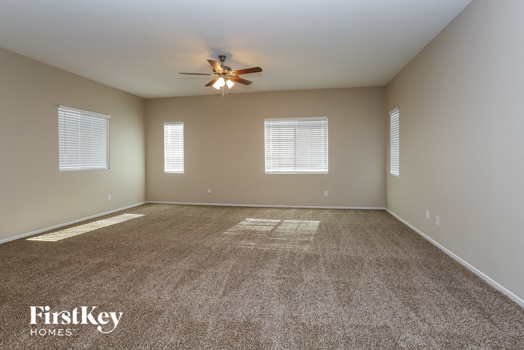 A spacious room with a ceiling fan and carpeted floor.