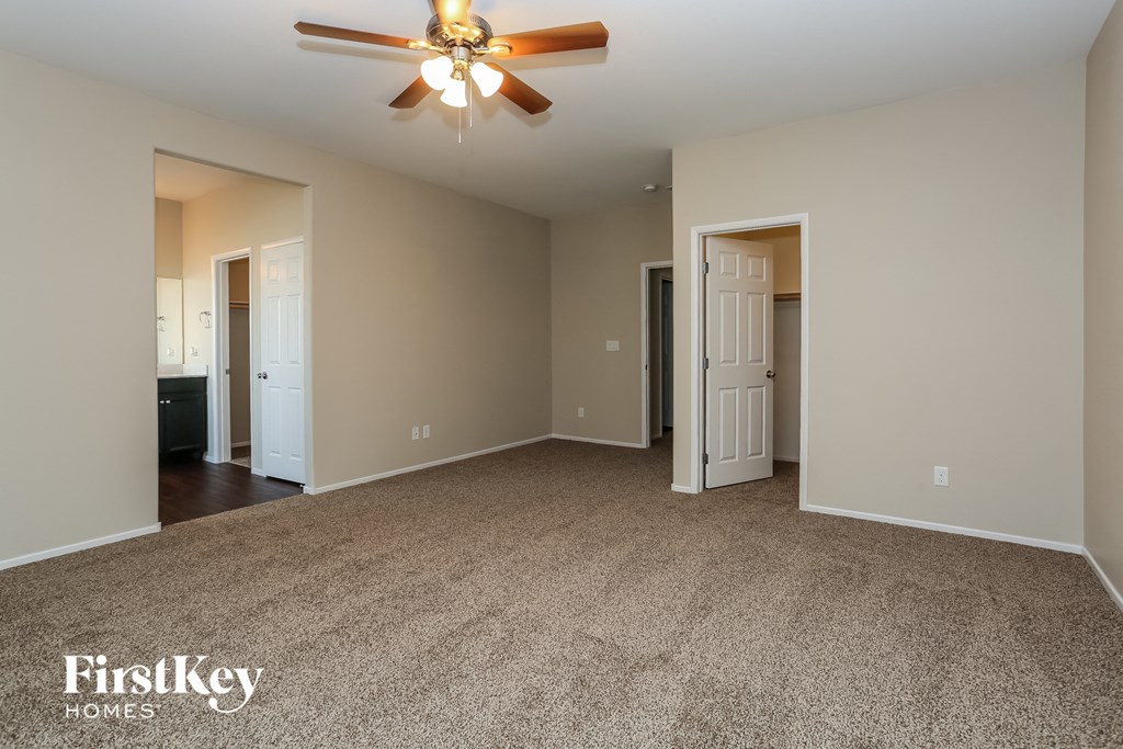 A spacious room with a ceiling fan and carpeted floor.