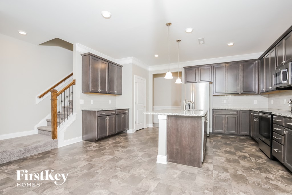 A kitchen and living room with a staircase on the left.