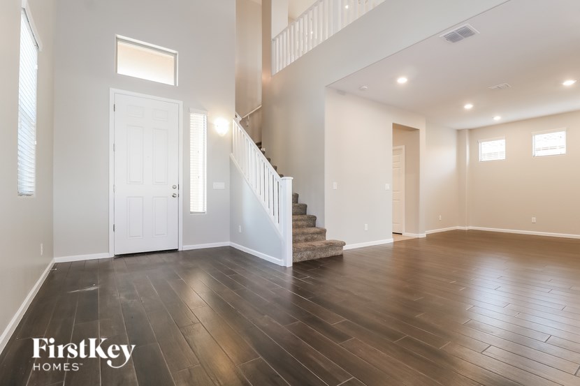 A spacious room with wooden floors and a staircase leading to another room.