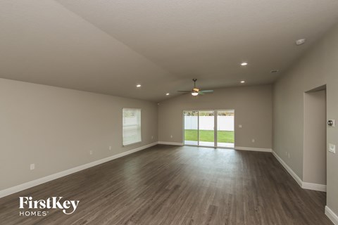 A spacious room with wooden floors and a ceiling fan.