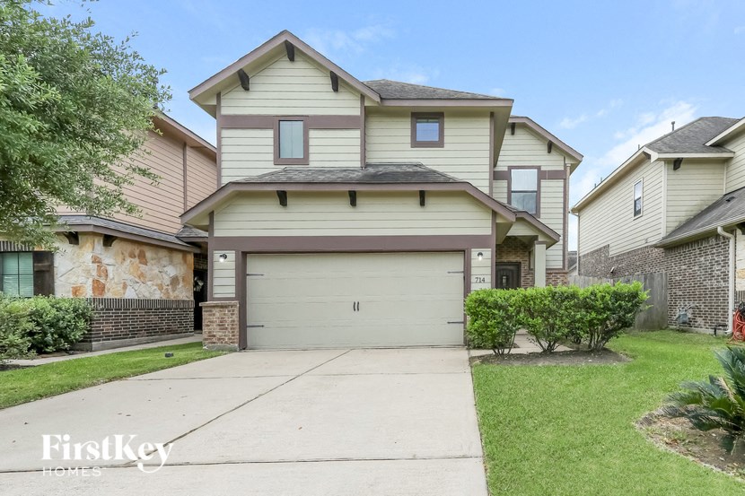 a white house with a white garage door in front of a green lawn