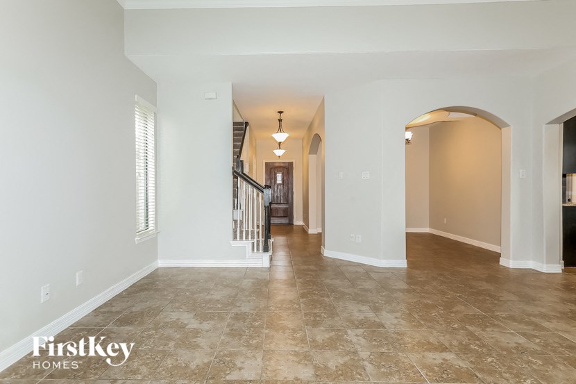 the living room and entryway of a house with white walls and tile floors