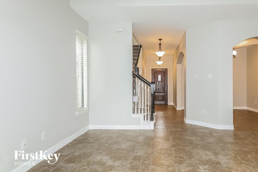 the entryway of a home with white walls and tile flooring