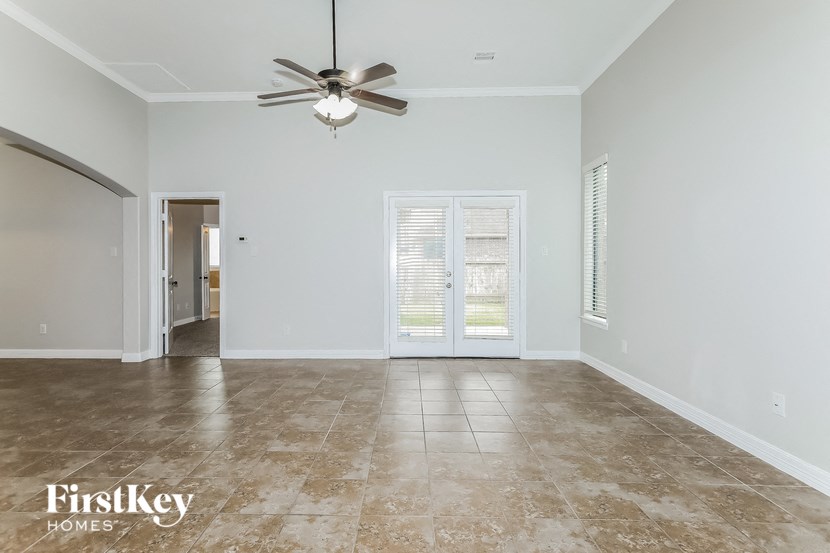 a empty living room with a ceiling fan and a door