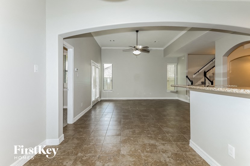 an empty living room and kitchen with a ceiling fan