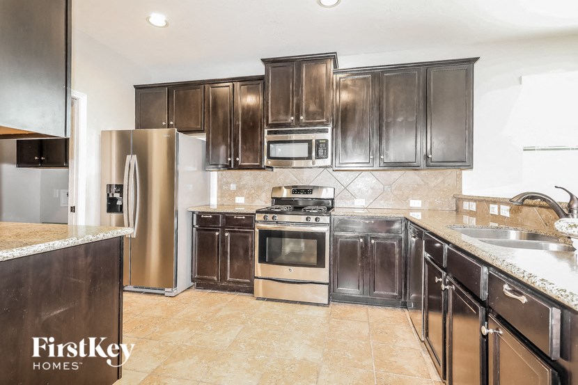 a kitchen with dark wood cabinets and stainless steel appliances