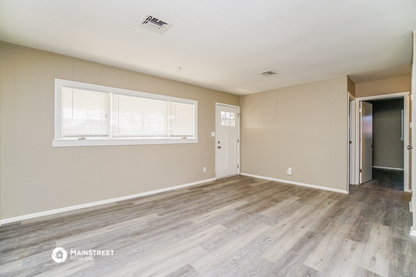 the spacious living room with wood flooring and a window