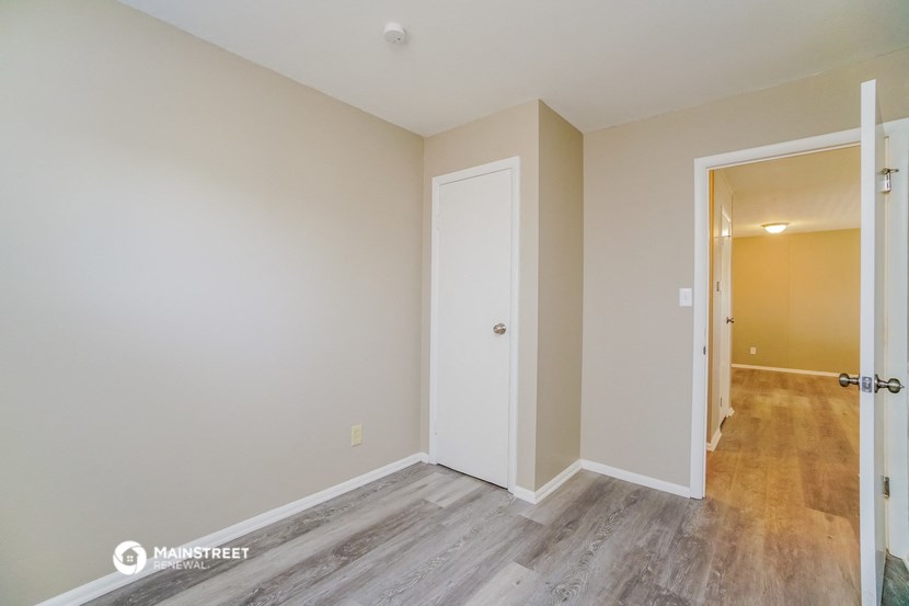a bedroom with wood flooring and a door to a hallway