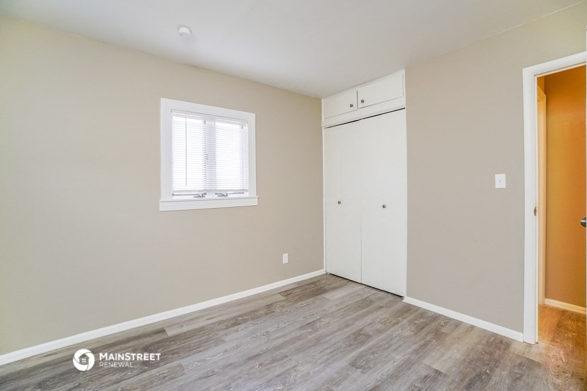 a bedroom with a closet and a window and wood floors