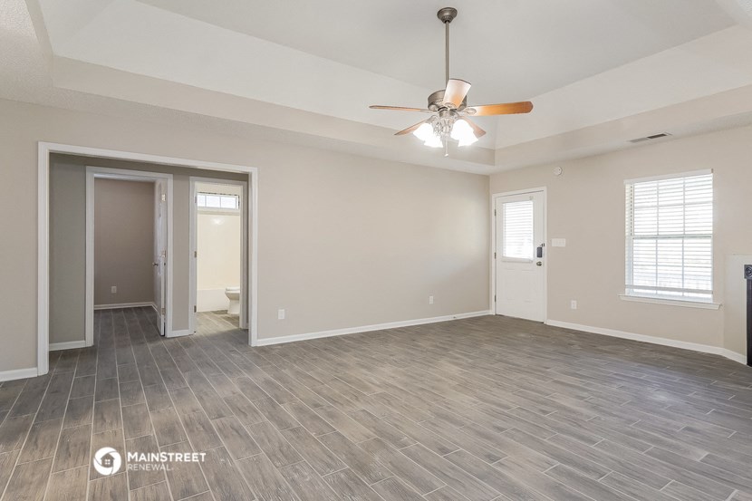 the living room of an empty house with a ceiling fan