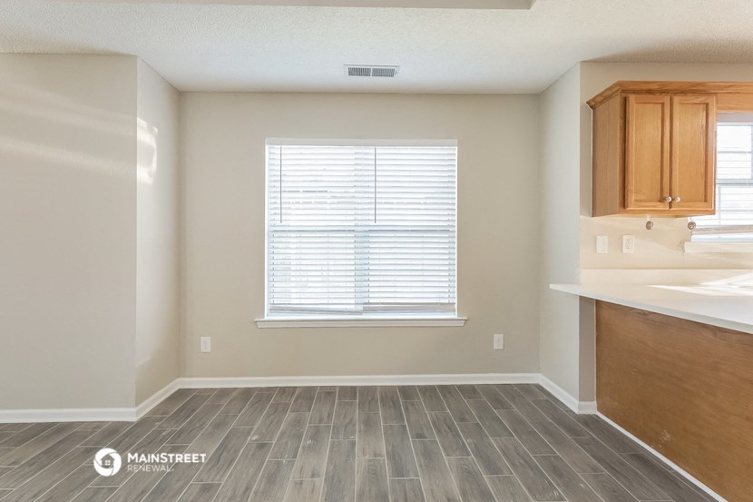 an empty kitchen with wood flooring and a window