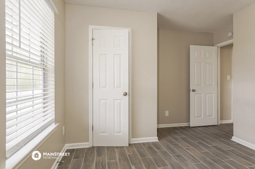 the living room of an apartment with two doors and a window