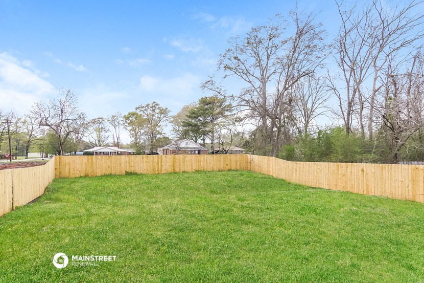 a fenced in backyard with a lawn and a wooden fence
