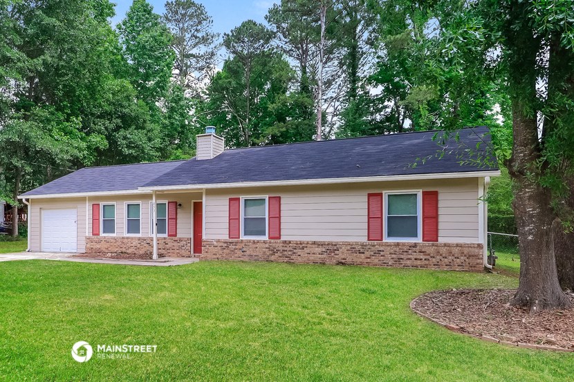 a small white house with red shutters and a grassy yard