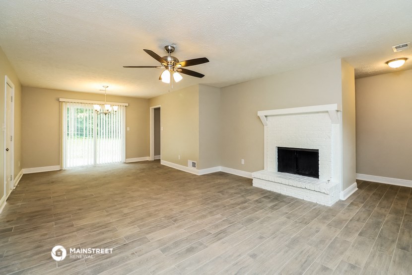 a living room with a fireplace and a ceiling fan