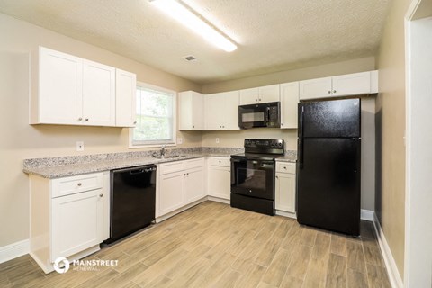 a kitchen with white cabinets and black appliances