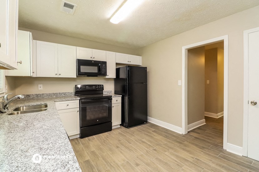 an empty kitchen with black appliances and white cabinets