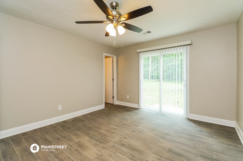 an empty living room with a ceiling fan and a window