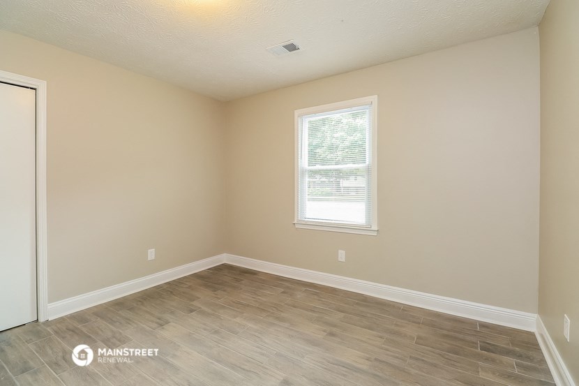the spacious living room with wood flooring and a window