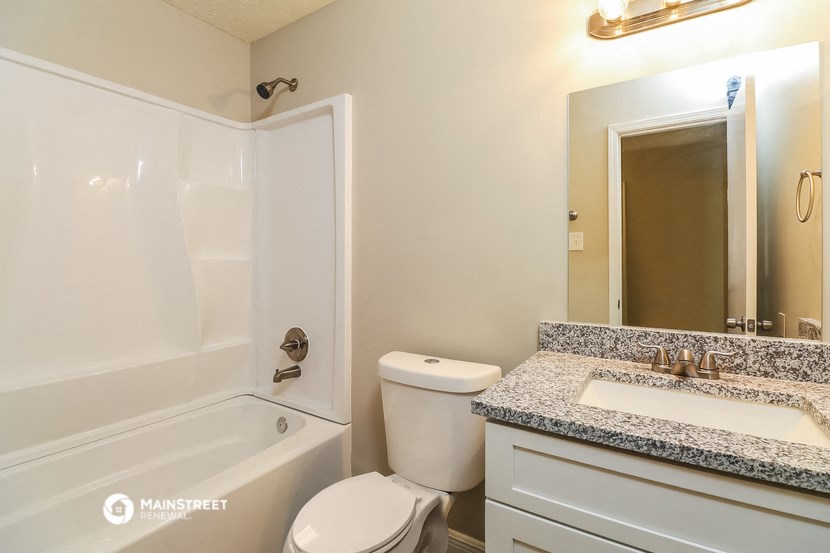 a bathroom with a toilet sink and tub and a mirror