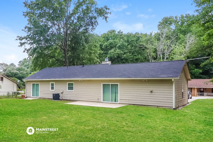 a small white house with green doors and a grassy yard