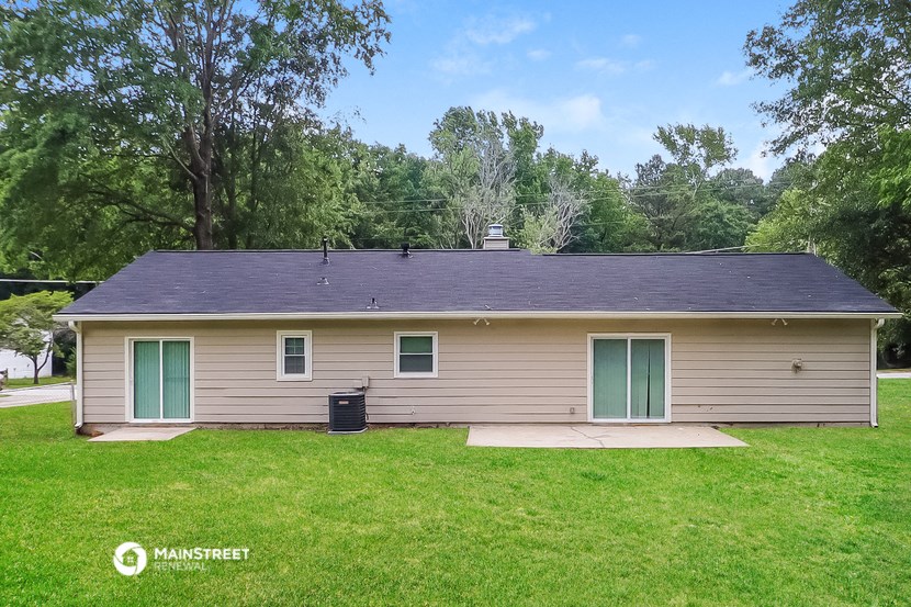 the front of a tan house with green doors and a grassy yard