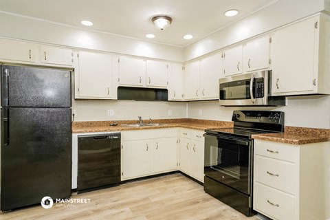a kitchen with white cabinets and black appliances and granite counter tops