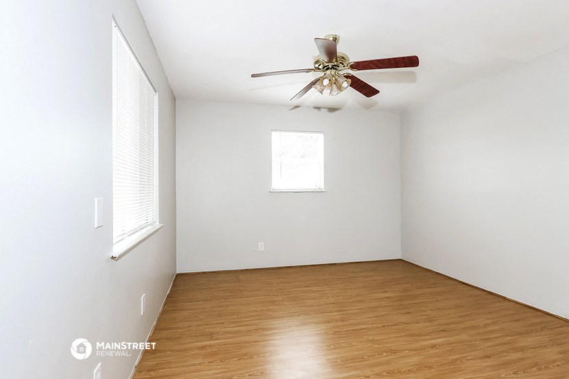 an empty room with a ceiling fan and wood floors
