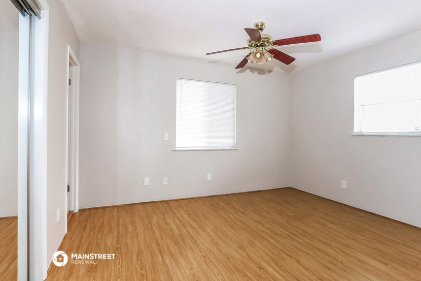 the living room with wood floors and a ceiling fan