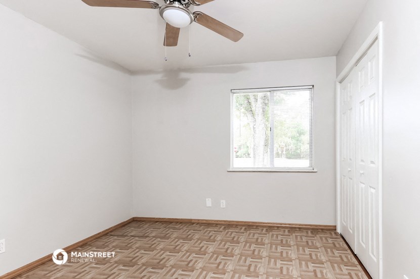 an empty room with a ceiling fan and a window