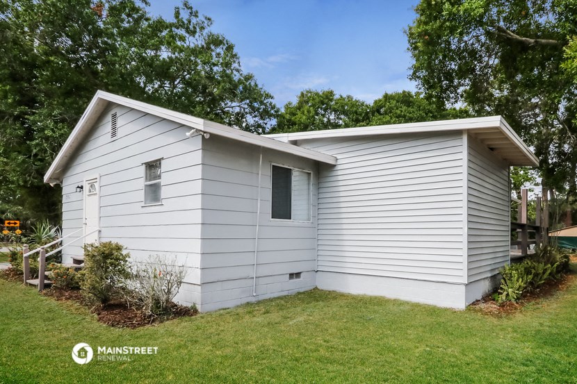 a small white house with a lawn and trees